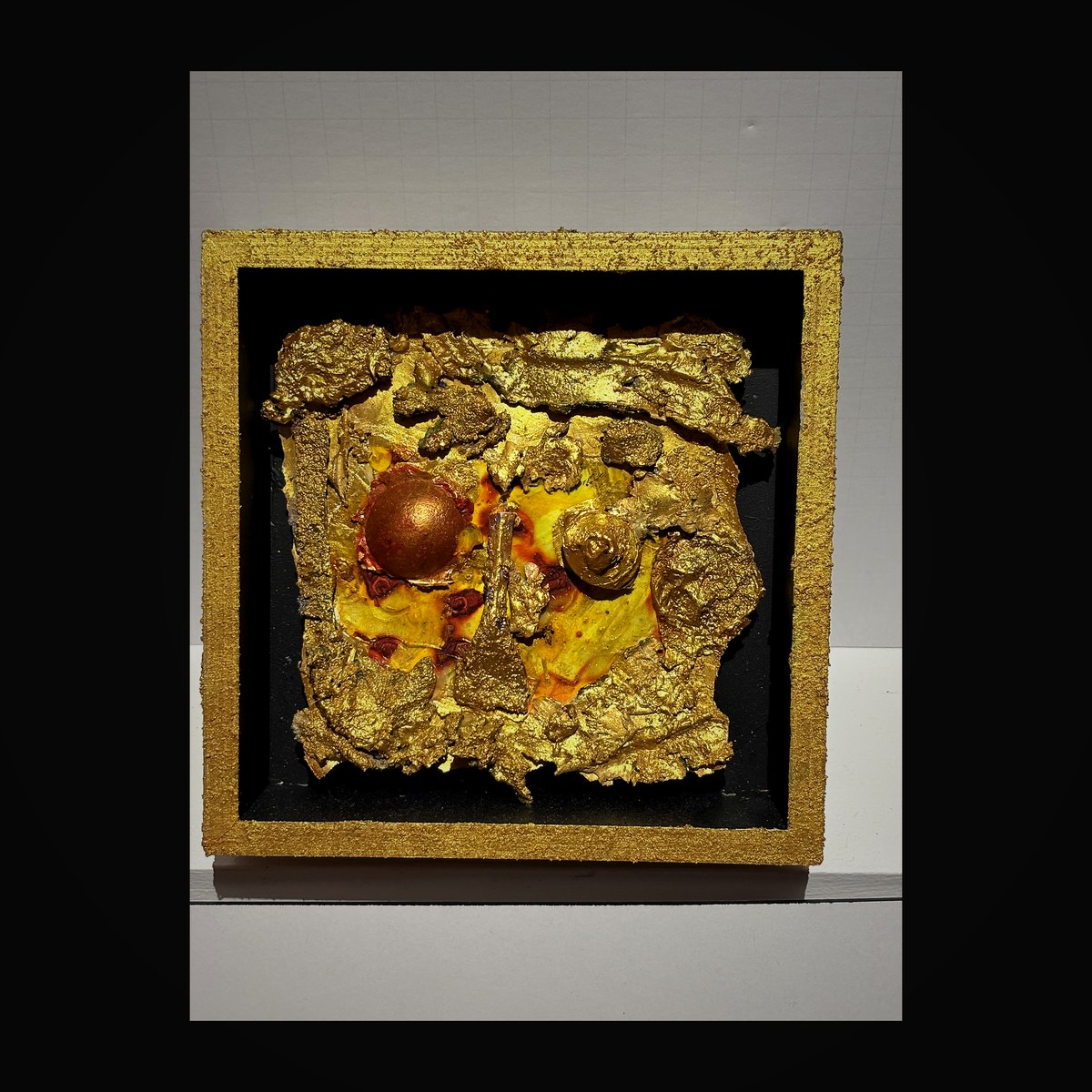 Gold leaf shadow box with central medallion surrounded by sculpted gold forms